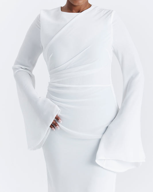 Women with white dress on standing with hand on hip.